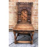 AN OAK HALL CHAIR, having a carved and inlaid back of geometric and floral design, 99cm high