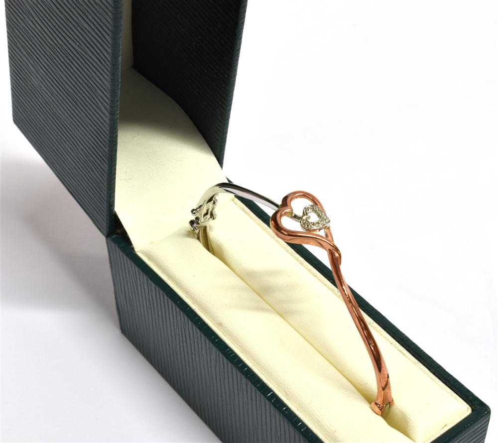 A 9CT ROSE AND WHITE GOLD HEART BANGLE the double heart openwork front set with very small