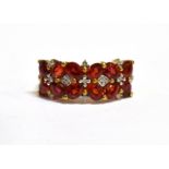 A MODERN RUBY TWO ROW AND DIAMOND SET GOLD RING A total of 12 small oval cut bright red rubies