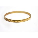 A 9CT GOLD CIRCULAR SLAVE BANGLE The circular bangle with stylised floral pattern and bead border,