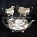 A SILVER THREE PIECE TEASET of cushioned shaped plain form with gadroon edging on 4 bun feet, teapot