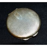 A SILVER COMPACT The round compact with engraved engine turned decoration to lid, engraved cartouche