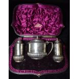 A CASED SILVER THREE PIECE CONDIMENT SET By Walter John Bernard of cylindrical design, the lidded