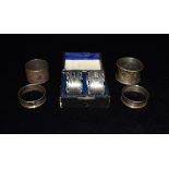 A QUANTITY OF SIX SILVER NAPKIN RINGS comprising a boxed pair with engraved initials, a pair of