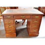 AN OAK TWIN PEDESTAL DESK, with a Rexine writing surface above a central drawer which is flanked