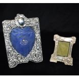 TWO SILVER PHOTO FRAMES The larger one of heavily embossed flower and scroll design with heart shape