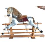 A CARVED WOODEN ROCKING HORSE the dapple-grey body with a horse-hair mane and tail, fitted with a