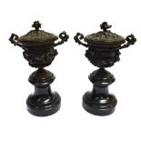 A PAIR OF BRONZE TWIN-HANDLED LIDDED VASES with naturalistic relief decoration, on waisted slate