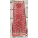 A RED GROUND BOKHARA RUNNER 69cm x 220cm