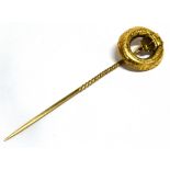 A VICTORIAN YELLOW METAL STICK PIN The top comprising a circular belt design with a barley twist