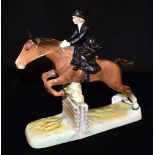 A BESWICK FIGURE OF A LADY RIDING SIDE SADDLE ON A BAY HORSE jumping a fence on a shaped rectangular