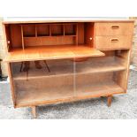 A 1960S TEAK SIDE CABINET/DISPLAY CASE fitted with sliding glass doors beneath pair of drawers and