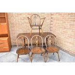AN ERCOL PLANK TOP DINING TABLE and set of four matching dining chairs with fleur-de-lys carved