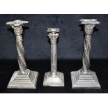 A SILVER CANDLE STICK AND A PAIR OF PLATED CANDLE STICKS The traditional Corinthian candlestick 25