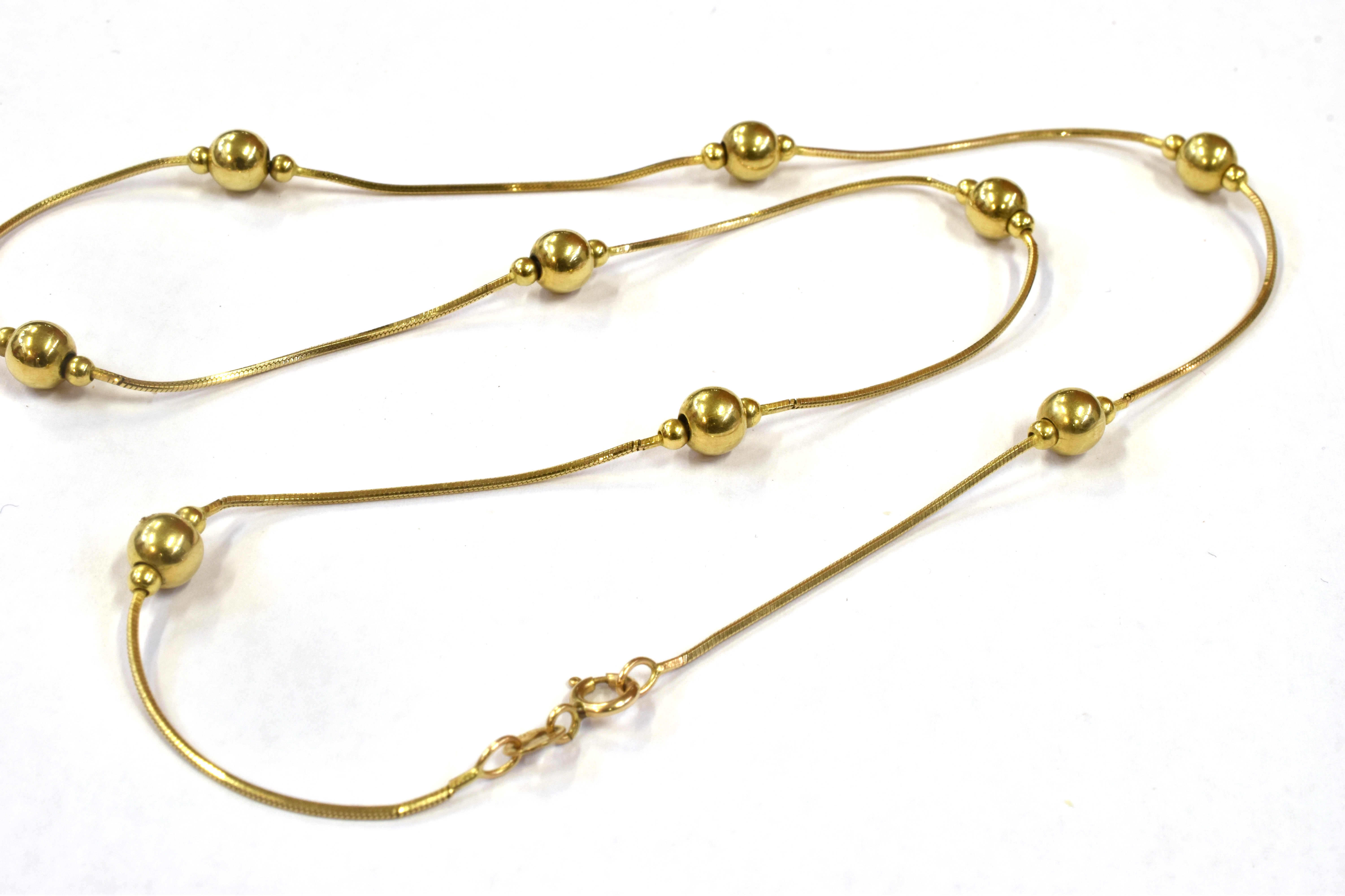 A HALLMARKED 9CT GOLD COLLARETTE The fine snake link chain with 9 round gold bead spacers, 16 inches