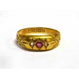 AN EDWARDIAN 18CT GOLD BAND RING Set with a small ruby and two small diamond chips, hallmark for