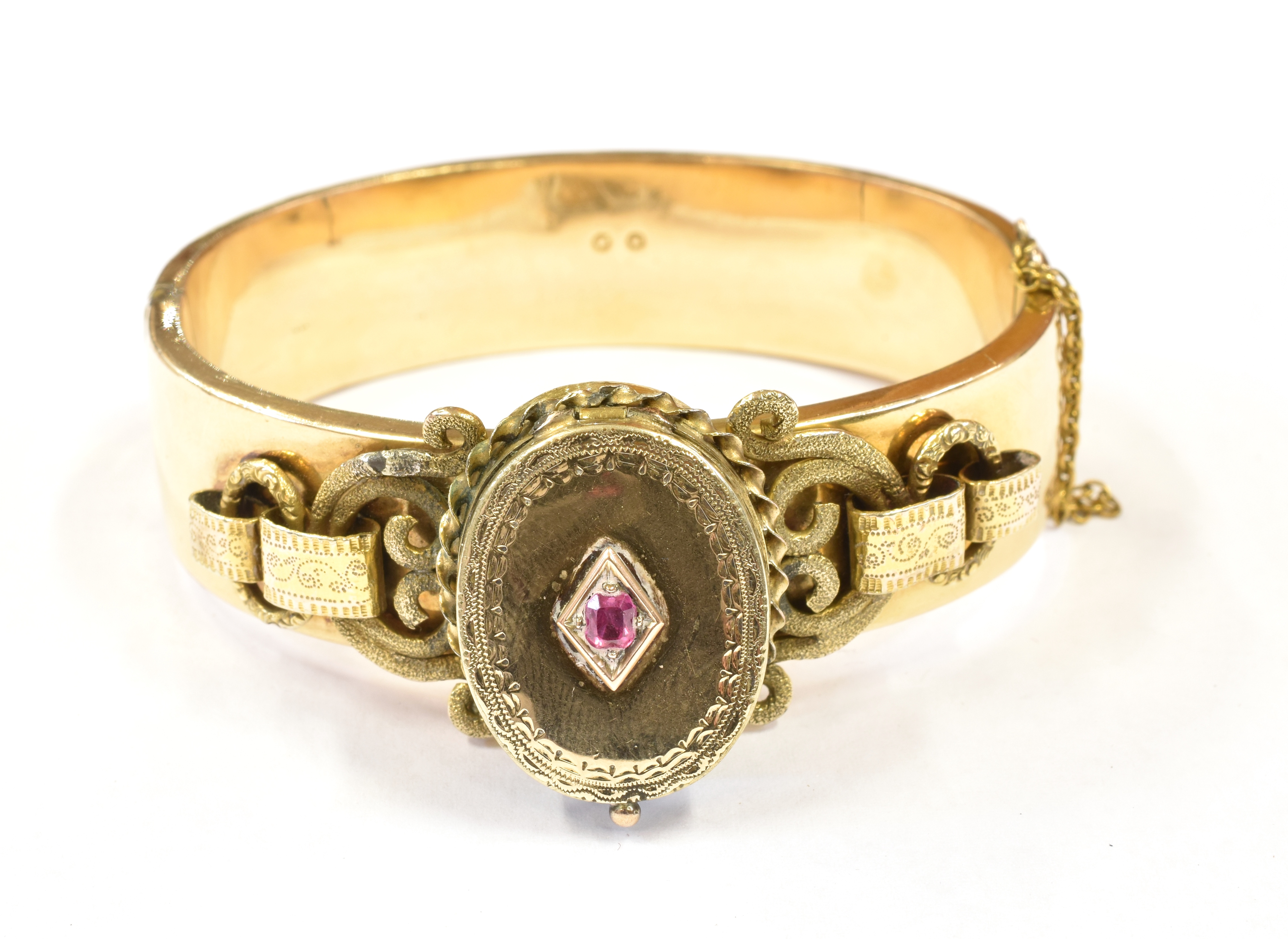 A LATE VICTORIAN BANGLE WITH LOCKET FRONT The oval hinged locket front set with a small ruby to