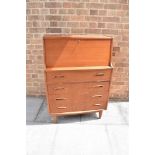 A 1960S TEAK G-PLAN STYLE BUREAU the fall front opening to fitted interior, above four drawers