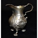 A VICTORIAN SILVER MILK JUG The baluster form jug on three feet with two embossed rural scene,