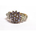 A TANZANITE CLUSTER DRESS RING The central multi tier cluster to diamond set shoulder and hallmarked