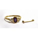 A 9CT GOLD AMETHYST AND WHITE STONE DRESS RING the central oval cut amethyst 6 x 4mm, three white