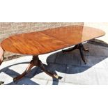 TWIN PILLAR MAHOGANY DINING TABLE, raised on central column with four outswept feet on casters,