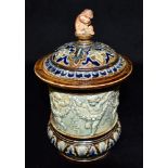 A DOULTON LAMBETH SALTGLAZE STONEWARE TOBACCO JAR the lid with figural finial, the body with