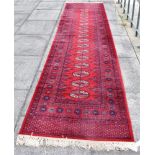 A RED GROUND BOKHARA RUNNER 91cm x 346cm