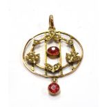 AN EDWARDIAN 9CT GOLD GARNET AND SEED PEARL DROP PENDANT The round openwork pendant with small red