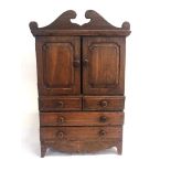 AN APPRENTICE PIECE FRUITWOOD CABINET, with a shaped cornice above a pair of doors opening to reveal