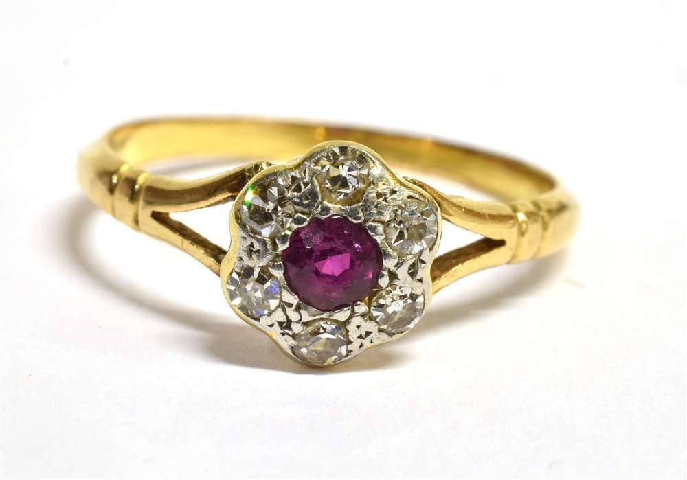 A RUBY AND DIAMOND 18 CT GOLD CLUSTER RING The round cluster comprising a small round cut ruby