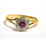 A RUBY AND DIAMOND 18 CT GOLD CLUSTER RING The round cluster comprising a small round cut ruby