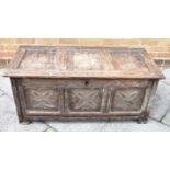 AN OAK COFFER, of small proportion, the top having three plain panels, and to the front carved