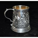 A SILVER SMALL MUG of tapering cylindrical form with s scroll handle and embossed floral