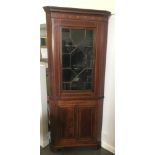 AN EDWARDIAN CORNER CABINET, the upper section having a cornice and glazed door, above two doors