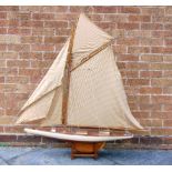A MODEL YACHT of wooden construction, the cream painted hull with a varnished deck and keel, in full