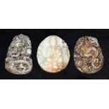 THREE CHINESE CARVED HARDSTONE PENDANTS one decorated with a seated deity, the other two decorated