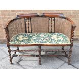 TWO SEATER SOFA, having a floral upholstered seat and with a cane back and raised on six barley