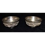 A PAIR OF CHINESE SILVER BOWLS Heavily embossed with dragons, measuring approx. 9.3 cm in diameter