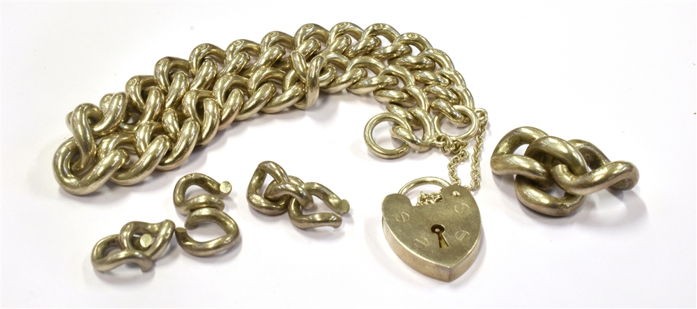 A SILVER CURB LINK BRACELET fitted with a silver heart padlock and safety chain with spare links,