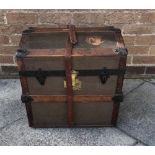 AN OAK AND LEATHER TRAVELLING TRUNK with leather carrying handles to each side the hinged top