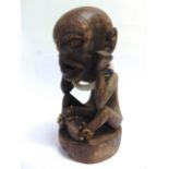 TRIBAL ART - AN AFRICAN CARVED WOODEN FERTILITY FIGURE in the form of a seated male, 41cm high.