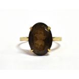 A 9CT GOLD QUARTZ COCKTAIL RING The large oval faceted purple tinted smoky quartz stone measuring