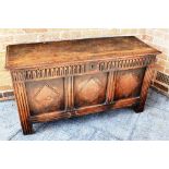 AN OAK COFFER OF PANELLED CONSTRUCTION the top opening to reveal candle box and an open storage