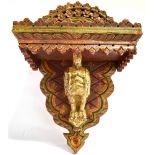 A CARVED AND PAINTED CLOCK BRACKET with floral carved and painted decoration, the surface for the
