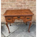 AN OAK LOW BOY with central drawer flanked to each side by a deep drawer and raised on cabriole