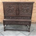 AN EBONISED CHEST ON STAND the upper section having twin doors each profusely decorated, opening