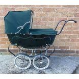 A DOLL'S PRAM the lined dark green body with a folding green hood and matching apron, on a sprung