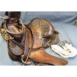 A VINTAGE WESTERN-STYLE TOOLED RIDING SADDLE together with a bridle and a cinch girth.