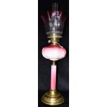 A LATE VICTORIAN/EDWARDIAN TWIN BURNER OIL LAMP with cranberry glass shade, pink opaque glass